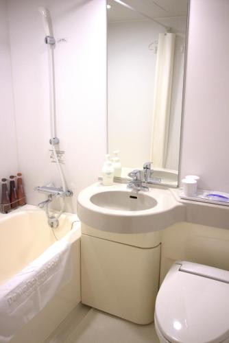 a bathroom with a sink and a toilet and a mirror at Daiwa Roynet Hotel Hiroshima in Hiroshima