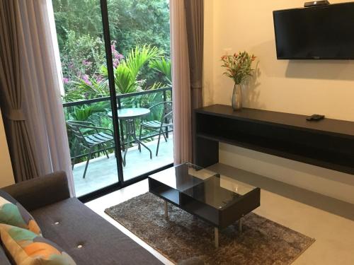 a living room with a couch and a table and a window at The Palm Residence in Hua Hin
