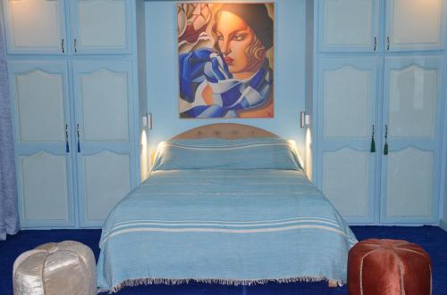 a bedroom with a bed with a painting on the wall at Residence 33 bleu in Guelmim