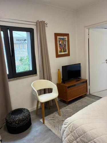 a bedroom with a bed and a chair and a television at Refúgio da Vila - Refuge of the Village in Vouzela