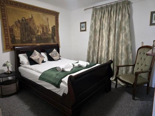 a bedroom with a bed and a chair and a painting at Cute Cottage in Egham Heathrow- 7 Guests 3 bedrooms in Egham