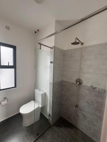 a white bathroom with a toilet and a shower at The Spring Collection in Tatu City