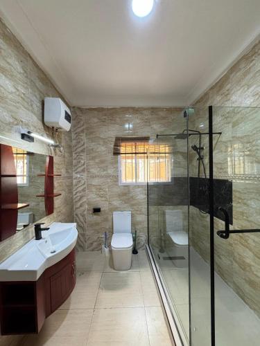 a bathroom with a shower and a toilet and a sink at Klue Homes in Maiyegun