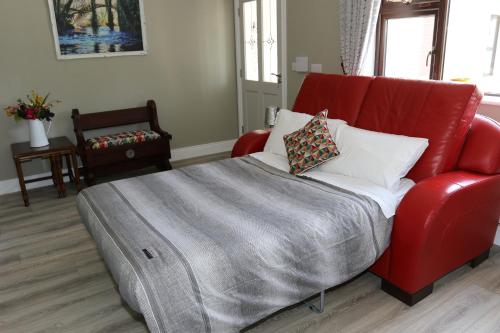 a red couch with a blanket on it in a room at Coaches Corner - Modern Suite - Sleeps 3 - Flexible Beds - Parking - Near Town in Castleblayney