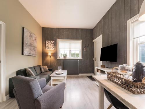 a living room with a couch and a tv at Holiday Home Egmond near Dune Beaches in Egmond-Binnen
