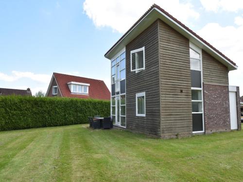 a house with a grass yard in front of it at Holiday Home in Flevoland with Pool in Zeewolde