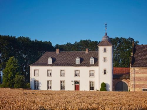 a large white house with a tower in a field at Stately 16-person manor farm in South Limburg in Schimmert