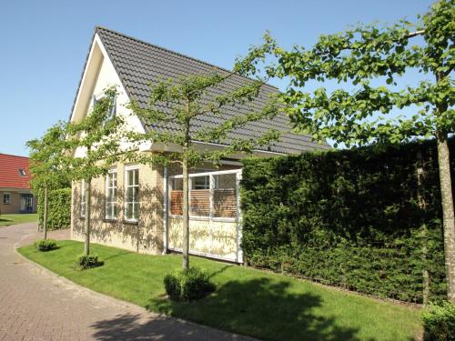 a small white house with a green hedge at Holiday Home in Schoorl near Sandy Beaches in Schoorl