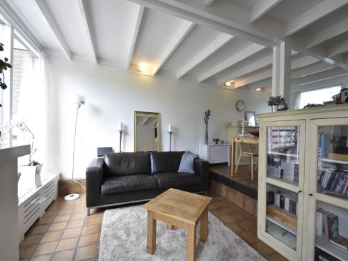 a living room with a black couch and a table at Holiday Home Warmenhuizen near Dunes in Warmenhuizen