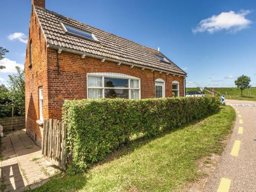 a brick house with a hedge next to a road at Holiday Home Nieuwvliet-Bad near Beach in Nieuwvliet-Bad