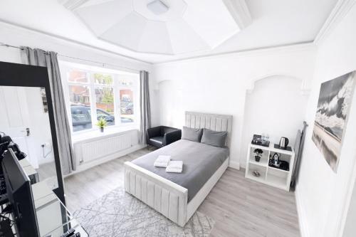 a white bedroom with a bed and a window at The Villas in Rock Ferry