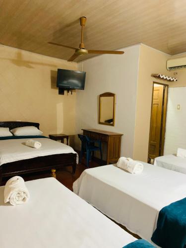 a room with three beds and a ceiling fan at Hotel San Andrés Mompox Ubicados en el Centro Histórico in Mompos