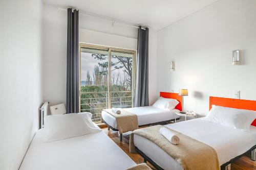 two beds in a room with a window at HI Porto - Pousada de Juventude in Porto