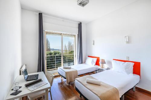 a room with two beds and a desk with a laptop at HI Porto - Pousada de Juventude in Porto