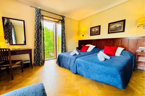 a bedroom with two beds and a desk and a window at Hotel Punta Me Torreblanca Palace in Guadarrama