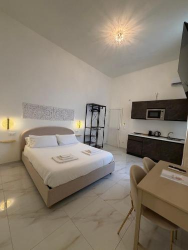a white bedroom with a bed and a table at Ippolita Palace LUXURY ROOMS in Otranto