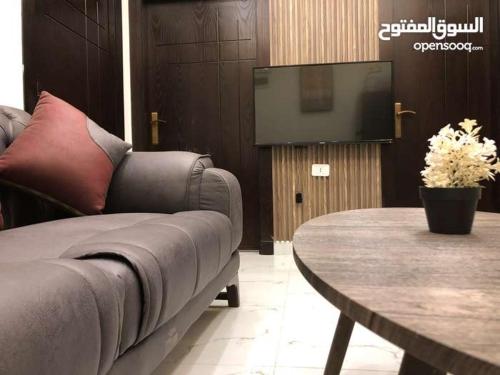 a living room with a couch and a table and a tv at شقة أنيقة-غرفتين وصالة مع بلكونة Stylish 2-Bedroom Apartment with Balcony in Amman