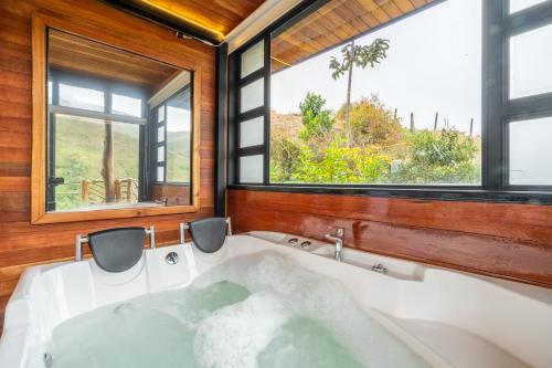 a bath tub in a room with windows at Mandrake Cabaña Nutria in Urrao
