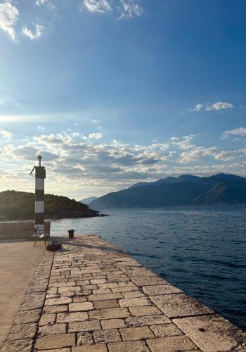a lighthouse sitting on a pier next to a body of water at BlueWave Apartments in Tivat