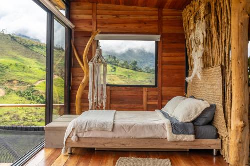 a bedroom with a bed and a large window at Mandrake Cabaña Nutria in Urrao