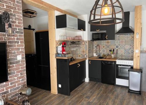 a kitchen with black cabinets and a brick wall at Vacances in Cavalaire-sur-Mer