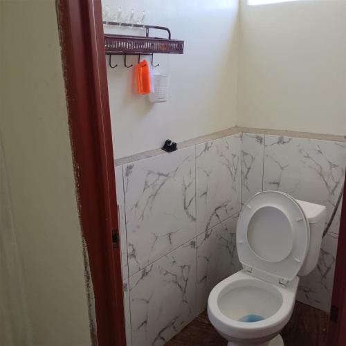 a bathroom with a white toilet and marble walls at Freundliche Kammer Transient House in Dahikan