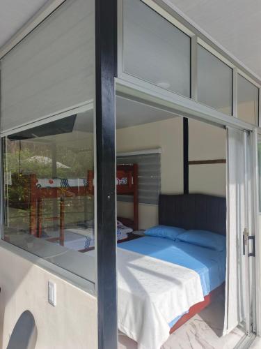 a bedroom with a bed and a glass window at Cabaña La Rivera in Macanal