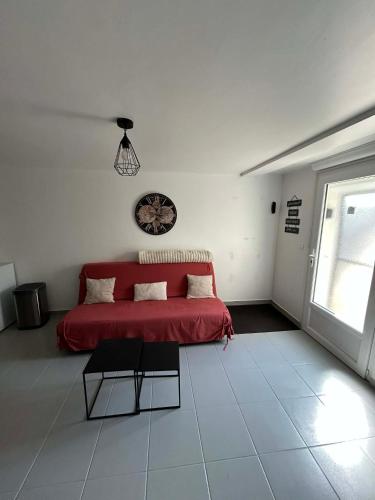 a white room with a red bed and a window at Le studio de Louisette in Châteaudun