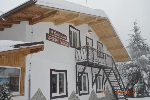 a building with a balcony in the snow at Cabana Groapa Seaca in Petroşani