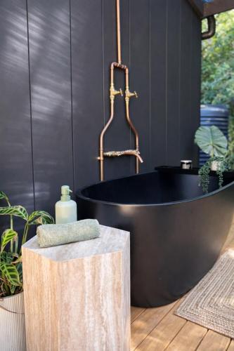 a black bathroom with a black tub and a sink at Wave and Willow Tiny Home in Broughton Village