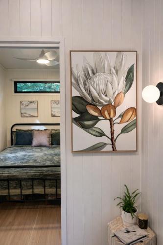a bedroom with a large flower painting on the wall at Wave and Willow Tiny Home in Broughton Village