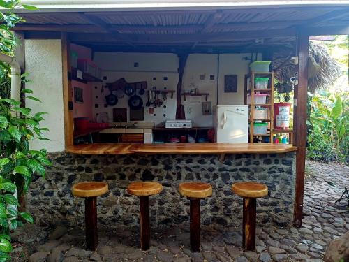 a counter with three wooden stools in a kitchen at La Urraca Loca Hostel in Balgue