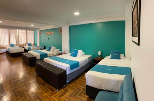 a room with three beds with blue and white at MATARA GREENS HOTEL in Cusco