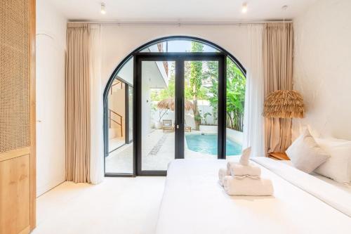 a bedroom with a white bed and a large window at Casa Myla Luxury Villa - Bingin in Badung