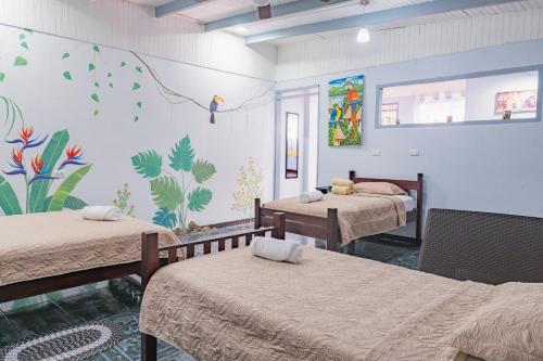 a room with three beds and a mural on the wall at Red Frog Rooms in Fortuna