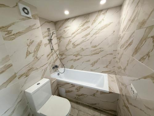 a bathroom with a toilet and a bath tub at Olimp Sea View Apartments by Maritimo in Olimp