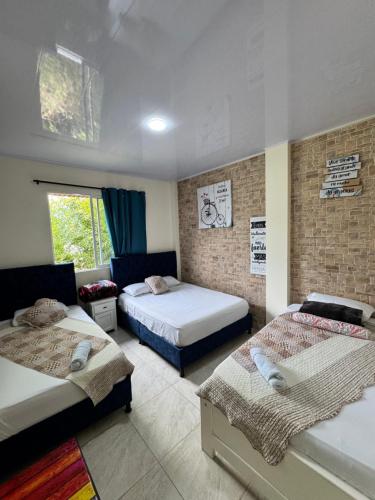 a bedroom with two beds and a brick wall at hospedaje El patio in Salento