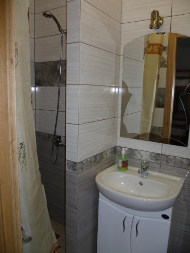 a bathroom with a sink and a shower with a mirror at Home Hotel in Kamianets-Podilskyi