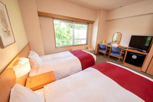 a hotel room with two beds and a television at Kyukamura Taishakukyo in Shōbara