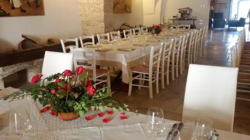 a long table with white tables and chairs with red flowers at Masseria Celentano Relais & Agriturismo in San Severo