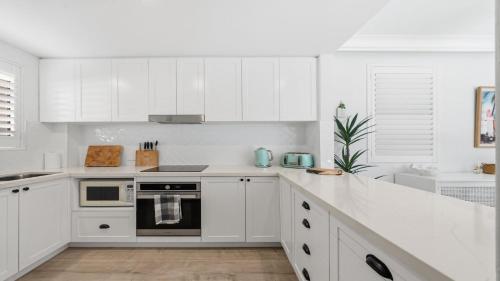 a white kitchen with white cabinets and appliances at Sea Glass in Terrigal
