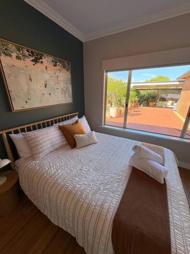 a bedroom with a large bed with a large window at Wonnerup Beach Manor in Wonnerup