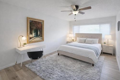 a white bedroom with a bed and a desk and a ceiling fan at Stay in the Heart of Hillcrest! in San Diego
