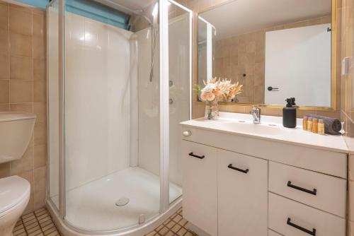 a bathroom with a shower and a sink and a toilet at Poinciana 106 in Hamilton Island