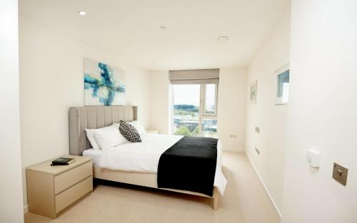 a white bedroom with a bed and a window at CityScape - Greenwich 2-Bed flat in London