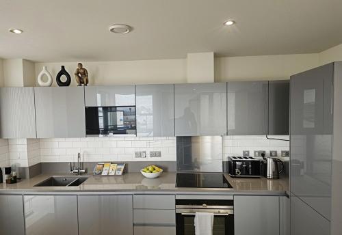 a kitchen with white cabinets and a sink at CityScape - Greenwich 2-Bed flat in London