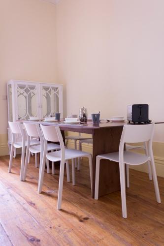 a wooden table with white chairs and a wooden floor at Canvas Atelier Hostel in Porto