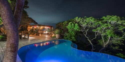 a pool in the middle of a garden at night at Pousada Enseada das Garças in São Pedro da Aldeia