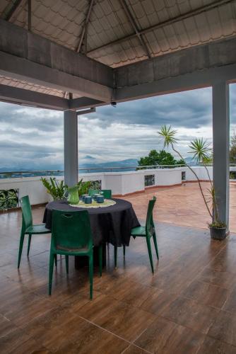 a table with green chairs on a patio with a view at Bethel Rest Homestay in Kandy