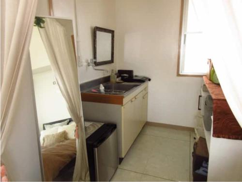 a small kitchen with a sink and a mirror at GUEST HOUSE SORA 2 in Okinawa City